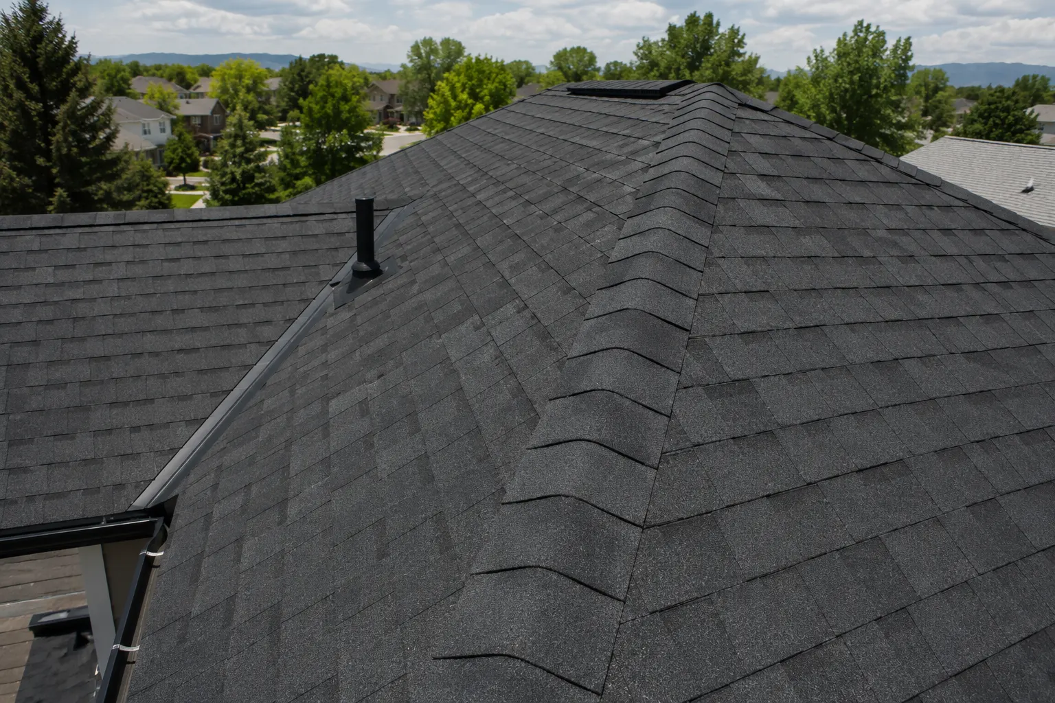 Aerial view of a new charcoal dimensional shingle roof on a home with the Colorado foothills behind it